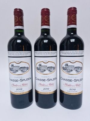 trois bouteilles de vin rouge posées l'une à côté de l'autre sur une surface blanche