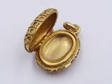 a gold locke with a picture inside of it on a white surface