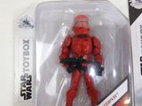 a red action figure in a plastic package on a table