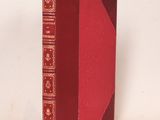 un vieux livre à la couverture rouge posé sur une surface blanche