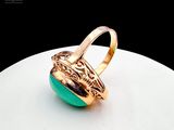 an image of a gold ring with a green stone on a white surface