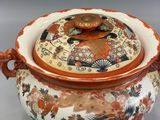 an orange and white bowl with a lid on a gray surface