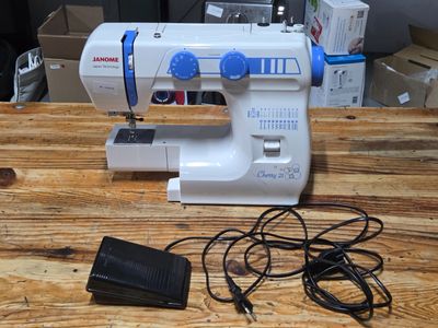a sewing machine sitting on a wooden table next to a charger