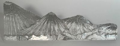 une sculpture métallique représentant une montagne avec, en arrière-plan, un sommet enneigé