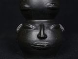a close up of a black vase with a face on it