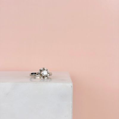 une bague de fiançailles posée sur un bloc de marbre blanc