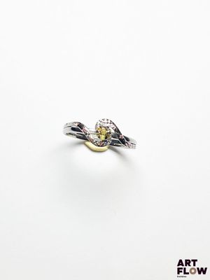 un gros plan d'une bague sertie d'un diamant jaune sur une surface blanche