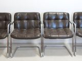 three brown leather chairs sitting next to each other on a white floor