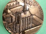 a silver medal with a picture of a building on it