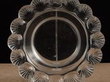 une assiette en argent posée sur une table, sur fond noir