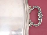 a silver tray with a handle on a red surface