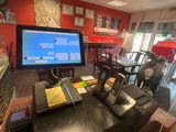 des tables et des chaises dans un restaurant où est accrochée au mur une télévision à grand écran