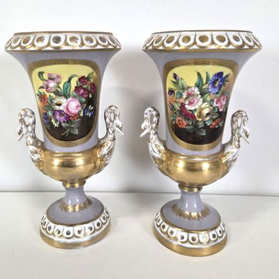 two vases with flowers painted on them sitting on a table