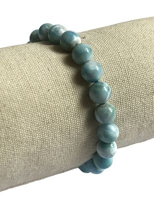 bracelet avec des perles bleues posé sur une serviette, sur fond blanc
