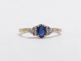 a close up of a ring with a blue sapphire and diamonds