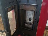 a red stove with a door open on a wooden floor