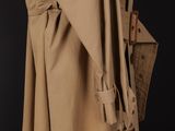 a woman in a trench coat with a purse on a black background