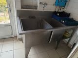 a sink in the corner of a kitchen with a door open