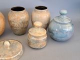 five different vases with lids sitting on a table