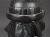 a silver helmet on a black stand against a gray background