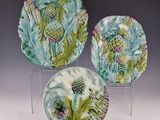three decorative plates with designs on them sitting on a clear stand