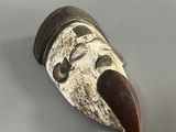 gros plan d'un masque en bois sur une surface blanche