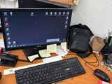 a desk with a computer, keyboard, mouse, and other items on it