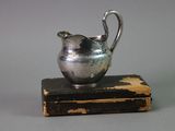 a small silver pitcher sitting on top of a book