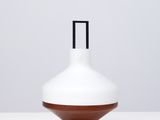 un vase blanc et marron posé sur une table blanche
