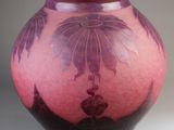 un vase rose orné de fleurs violettes, posé sur un fond blanc