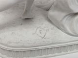 a white figurine of a woman on a bed