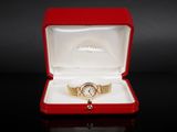 an image of a gold watch in a red box on a black surface