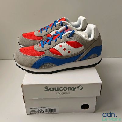 baskets Saucony grises et rouges présentées dans une boîte blanche