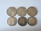 six different coins sitting on top of each other on a white surface
