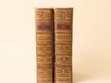 deux vieux livres posés l'un sur l'autre sur une surface blanche