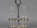 two glass vases and a silver plate with a handle on a stand