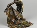 une statue représentant un homme assis sur une couverture