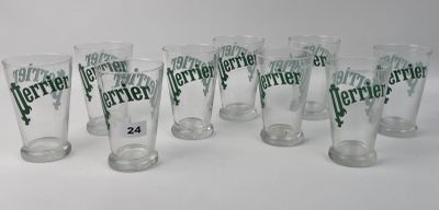 six verres transparents portant des inscriptions vertes sont alignés sur une surface blanche