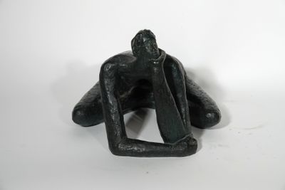 statue of a man sitting on his knees on a white surface