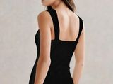 a woman in a black one piece swimsuit standing on a stool