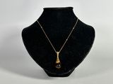 a black and gold necklace on a black mannequin