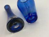 two blue glass bottles sitting on a white surface