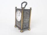 une petite horloge posée sur une surface blanche