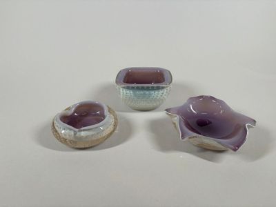 three pieces of pottery sitting on top of a white table