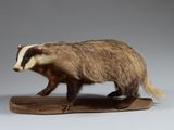 une figurine représentant un blaireau, posée sur un socle en bois