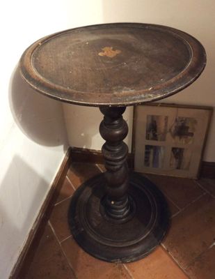 une petite table avec un plateau en métal posée sur un sol carrelé
