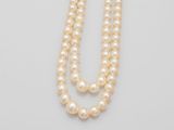 a close up of two strands of pearls on a white surface