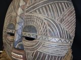 an image of a wooden mask on a stand with a black background