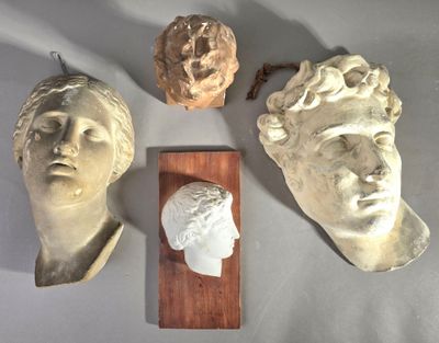 trois têtes de statues sont exposées sur une table, accompagnées d'une plaque en bois