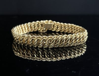gros plan d'un bracelet en or sur une surface noire